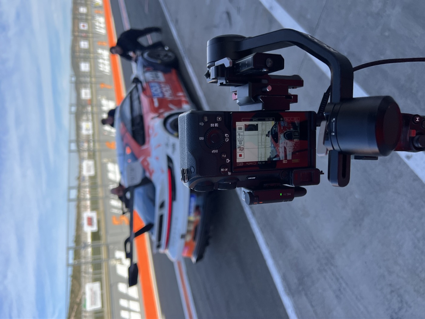 Cámara en estabilizador grabando un coche de competición en el pit lane de un circuito